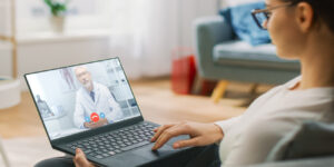 Young woman at home video chats with her physician on her laptop